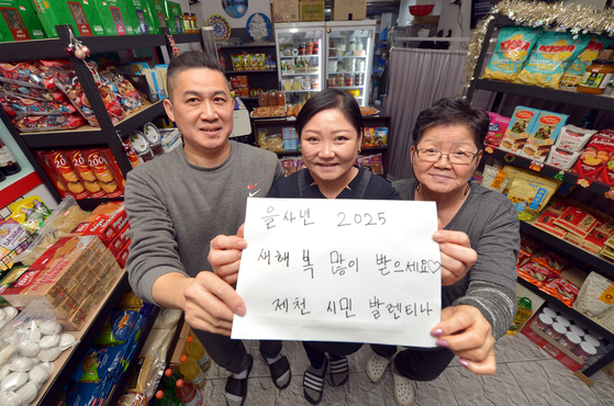 충북 제천에 정착한 고려인 발렌티나(가운데)와 그의 어머니 리다(오른쪽), 남편 알렉세이가 지난 23일 식료품점 안에서 새해 축하 메시지를 들고 있다. 프리랜서 김성태