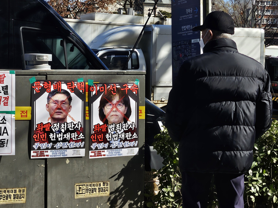 13일 헌법재판소 인근 지하철 3호선 안국역 5번 출구 앞에서 문형배 헌법재판소장 권한대행과 이미선 헌법재판관 얼굴이 그려진 포스터를 한 시민이 쳐다보고 있다. 서지원 기자