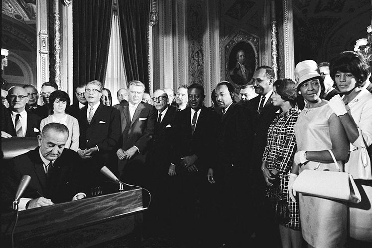 1965년 8월 6일 린든 존슨 대통령이 마틴 루터 킹 목사 등이 지켜보는 가운데 투표권리법에 서명을 하고 있다.