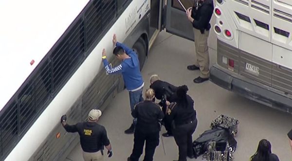체포된 CVE 테크놀러지 직원을 버스에 태우기 전에 ICE 요원들이 몸을 수색하고 있다.