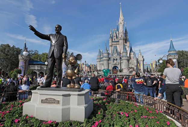 A statue of Walt Disney and Mickey Mouse stand at the foregrounds of Disneyland. [Source: Associated Press, John Raoux]