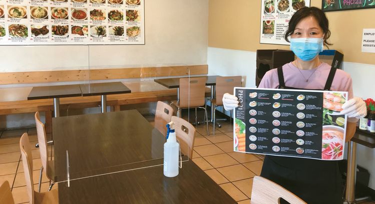부에나파크의 ‘포21’ 식당 직원이 다인 인 영업을 위해 마련한 일회용 메뉴를 보여주고 있다. 이 식당은 테이블에 아크릴판 칸막이도 설치했다.