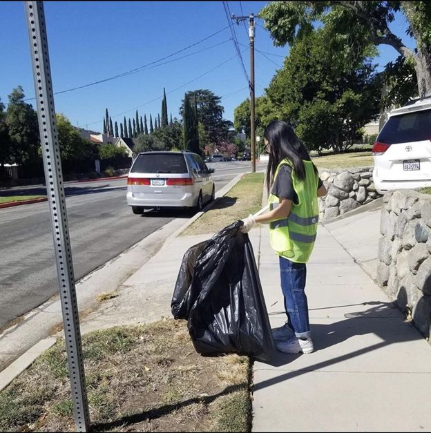 Here is a picture of a student cleaning up the trash in the neighborhood during her lunch break. 