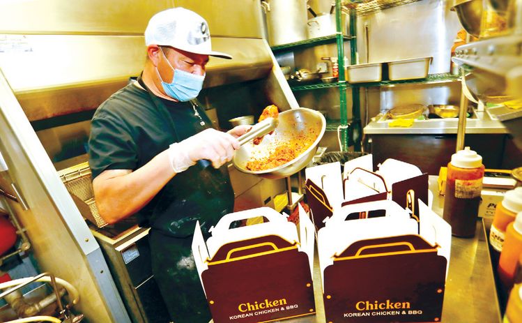 치킨 가격이 연일 치솟으면서 치킨점들이 어려움에 직면했다. LA한인타운에 있는 꼬끼오치킨 K타운의 직원이 바삭하게 튀긴 닭을 포장에 담고 있다. 김상진 기자   
