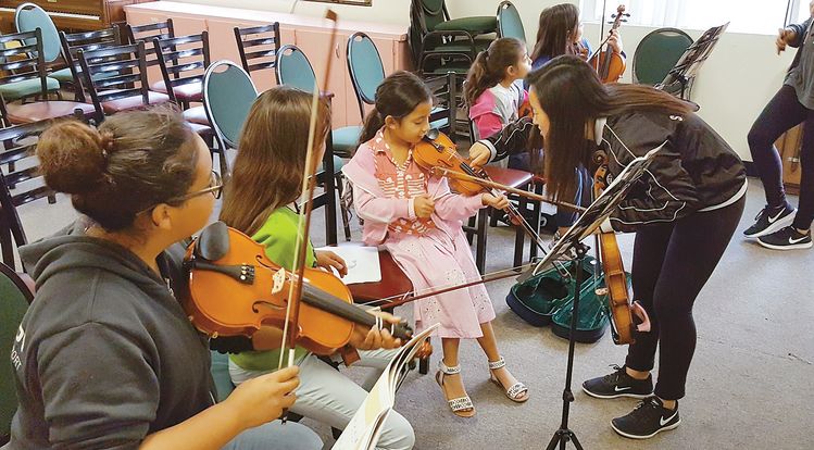 남가주 한인 음악교습 단체 '러브인뮤직'이 최근 1만 달러 기부금을 전달 받았다. 사진은 셀리스 이(오른쪽) 양이 러브인뮤직 봉사자로 활동하면서 타인종 학생에게 바이올린 연주를 가르치고 있는 모습. [러브인뮤직 제공]