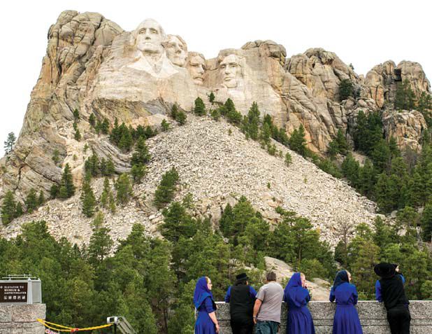 러시모어산에 새겨진 미국 대통령들의 거대한 얼굴 조각상을 관광객들이 올려다보고 있다. 왼쪽부터 조지 워싱턴, 토머스 제퍼슨, 시어도어 루즈벨트, 에이브러햄 링컨.