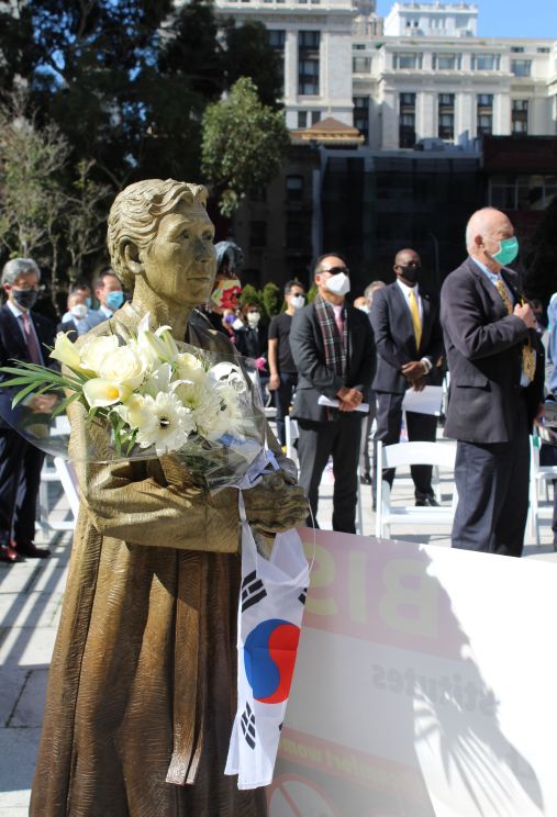 고 김학순 할머니 동상 손에 꽃과 태극기가 걸려 있다.