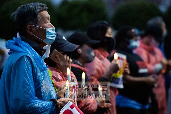 지난 26일 둘루스 뷰티마스터 앞에서 열린 ‘애틀랜타 총격 희생자 추모 촛불집회’ 참석자들이 희생자를 위해 기도하고 있다. [사진 전형미 차장]