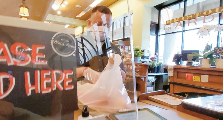 사우스 패서디나에 있는 브리스톨팜의 계산대 직원이 일회용 비닐에 손님이 구입한 물건을 담고 있다. 