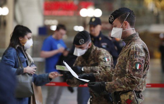 이탈리아 군인과 경찰이 밀라노의 기차역에서 도시를 떠나려는 사람들의 통행서류를 하나하나 확인하고 있다. [AP=연합뉴스]