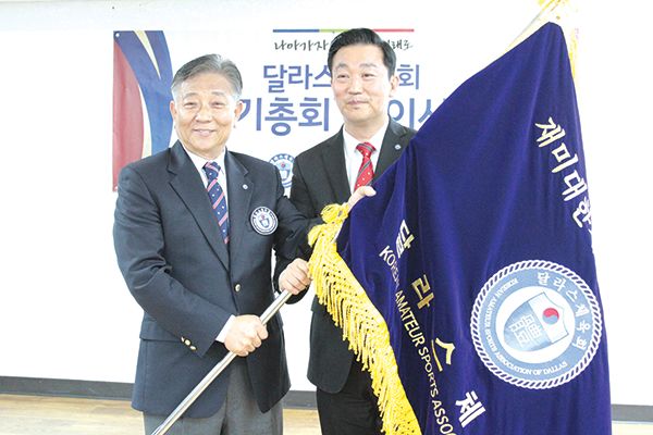 달라스 체육회 황철현 전임 회장(왼쪽)이 김성한 신임 회장에게 협회기를 이양했다. 