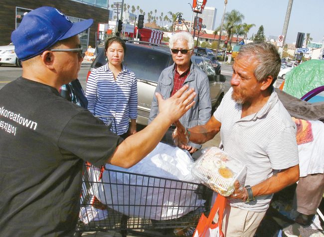 LA 한인회 제임스 안 이사(왼쪽)가 한인타운 올림픽불러바드와 카탈리나스트리트 코너에서 3년째 노숙 생활을 하고 있는 알렉스와 하이 파이브를 하고 있다. 김상진 기자